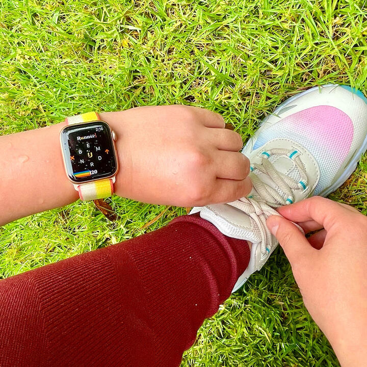 Person tying running shoes wearing Apple Watch displaying Retrogram game screen