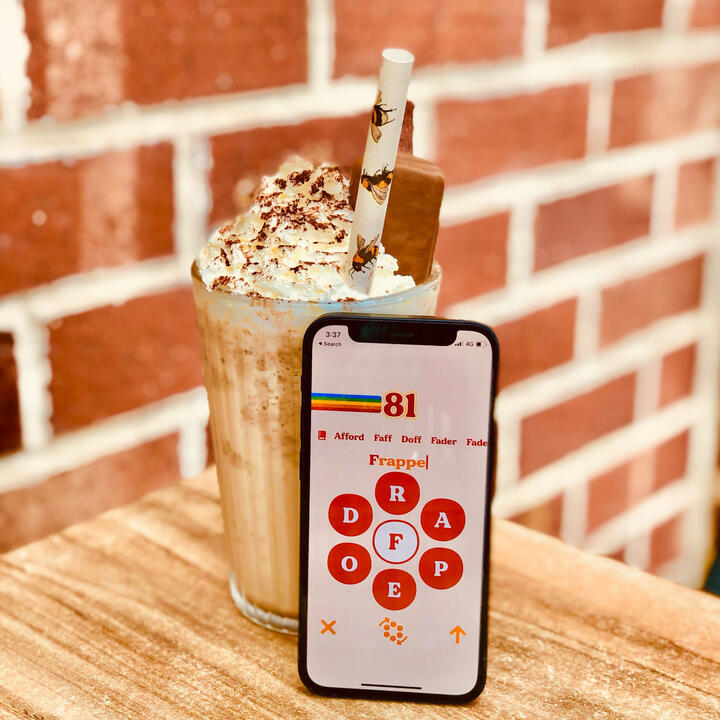 iPhone standing next to frappe with whipped cream, iPhone is displaying Retrogram game screen